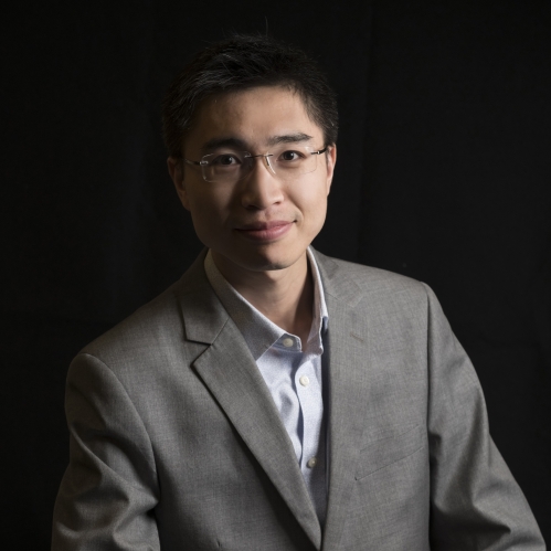 Short hair Asian man in eyeglasses wearing a grey suit with a light grey shirt