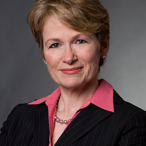 head shot of female with short light brown hair wearing a black suit jacket with rose colored shirt