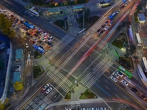 Aerial view of a roadway intersection showing cars moving.