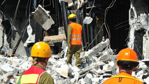 Photo of three engineers walking among rubble from and earthquake