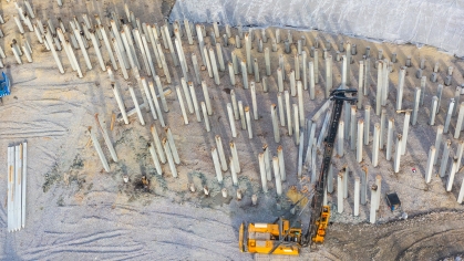 Equipment for installing piles in ground, heavy machines for driving pillars work in laying the foundation building. Construction aerial view height.