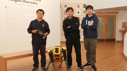 Professor with two male students working in Zimmerli Museum with a robotic dog.