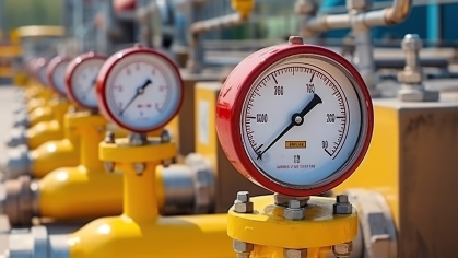 Red pressure meters on yellow natural gas pipelines.