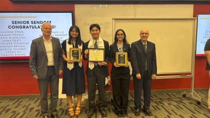 Three students holding awards as they are flanked by two male faculty.