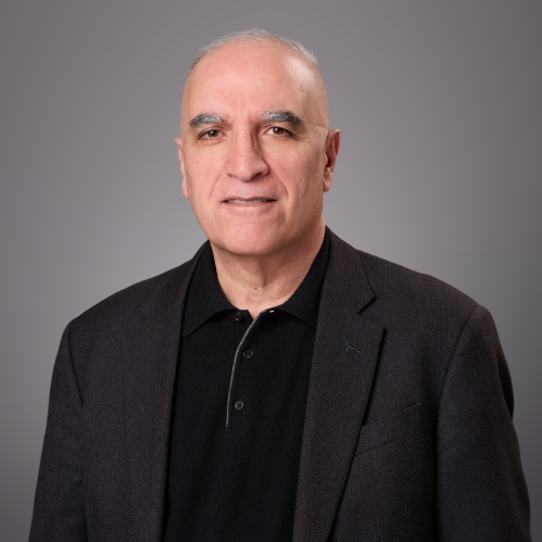 Headshot of male with short grey hair wearing a black button down shirt and a black suit jacket.
