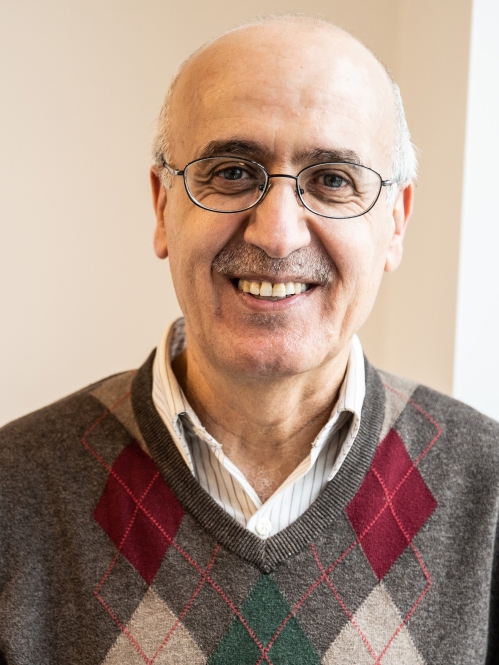 head shot of bald man in eyeglasses wearing a plaid pullover sweater