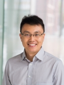 head shot of asian man with short hair and eyeglasses wearing a button down shirt