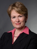 head shot of female with short light brown hair wearing a black suit jacket with rose colored shirt