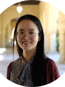 Headshot of Chinese woman with long black hair wearing eyeglasses and a blue and white patterned blouse.