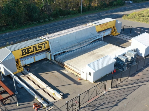 Aerial shot of a testing facility that includes a long structure and two connected small buildings. The long structure is yellow with the word BEAST in big black letters.