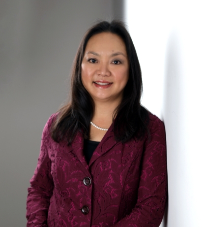 Headshot of woman with black hair, wearing a burgundy suit jacket, black shirt, and pearl necklace.