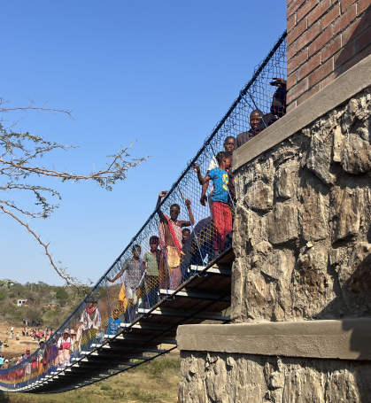 Many children and adults standing all along the footbridge, as they cross to the other side