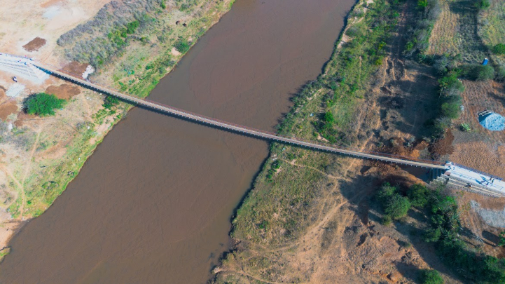 Aerial shot of the bridge from high up, with the river below it, and both embankments in frame
