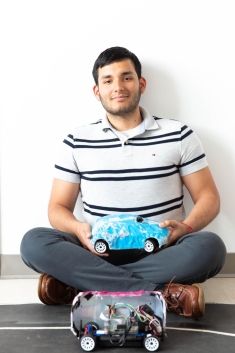 Photo of Victor Abril seated on the floor with model cars 