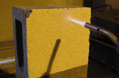 Yellow painted concrete block being exposed to a flame.